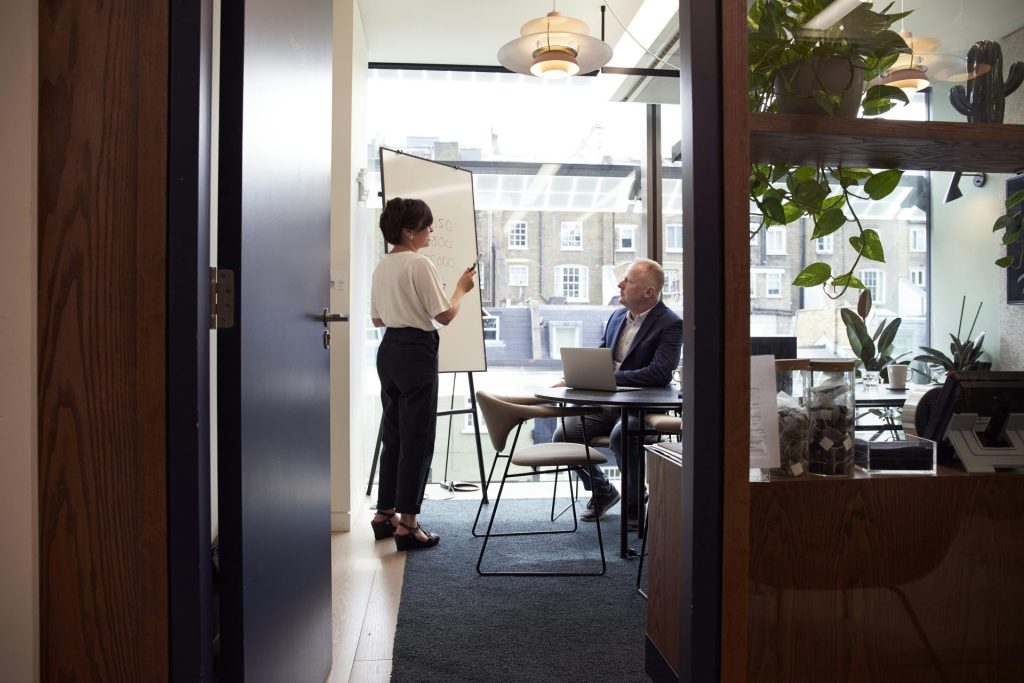 Kollegen führen ein strategisches Geschäftstreffen in einem modernen Londoner Büro mit Blick auf die Stadt.
